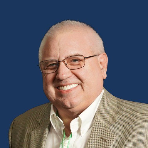 Jay Olivo, smiling, in glasses and a light jacket.
